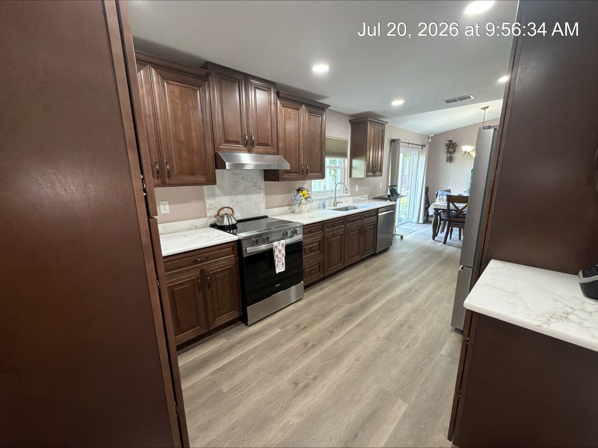 Remodeled galley kitchen with walnut cabinets opening to a dining area