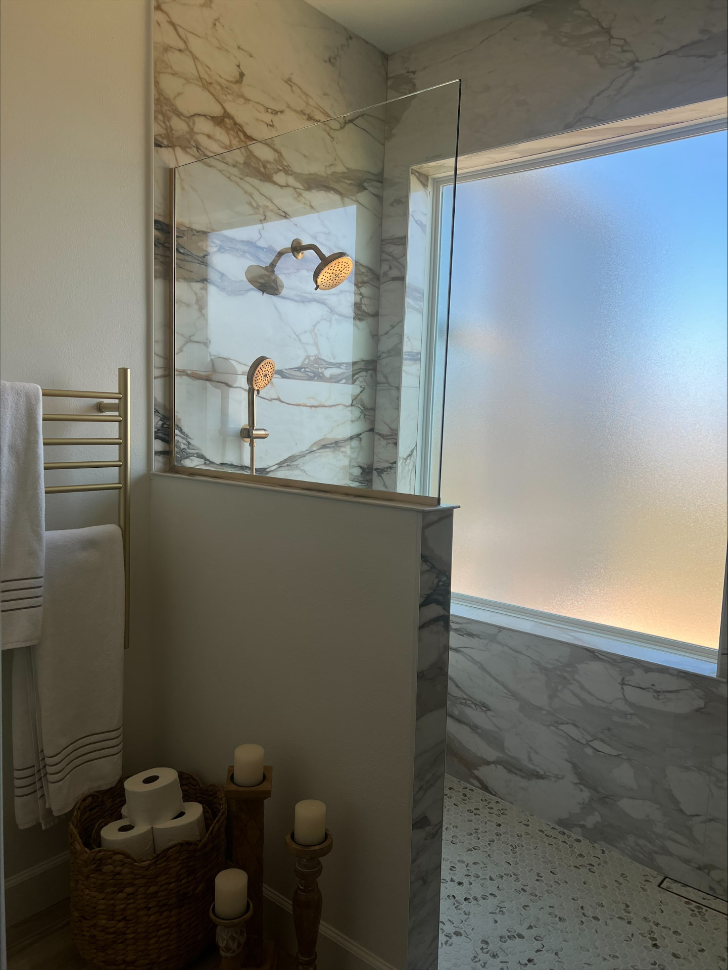 Marble shower with glass partition, privacy window and heated brass towel rack