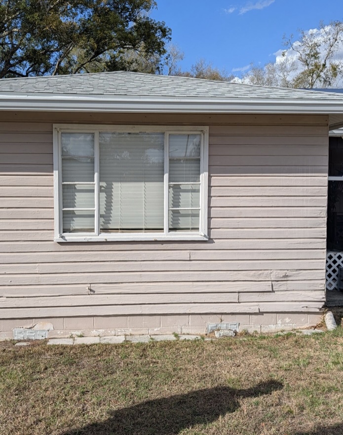 Existing home exterior with aging lap siding and settled block foundation before restoration work