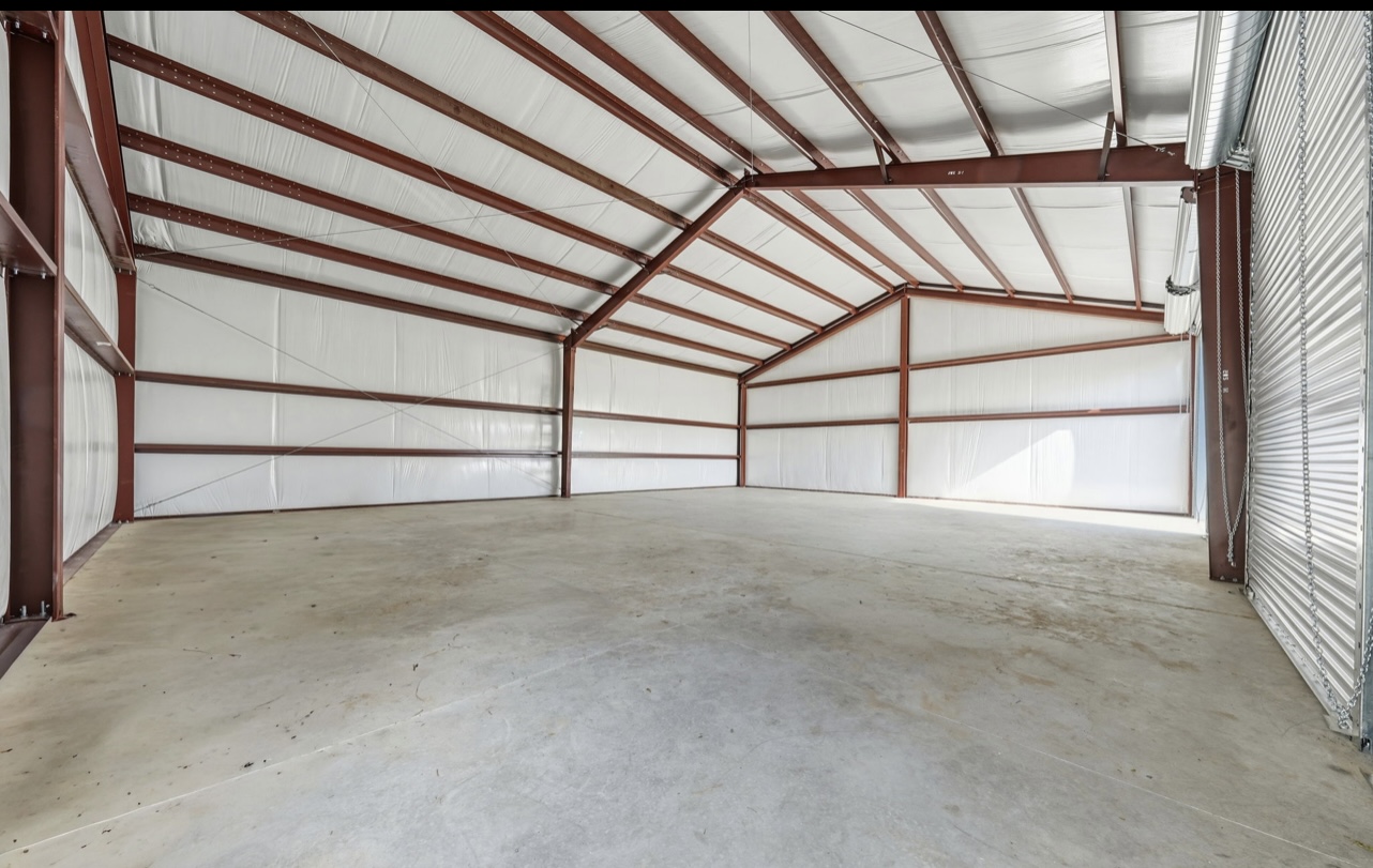 Insulated steel building interior with white liner panels, red-iron columns and a finished slab