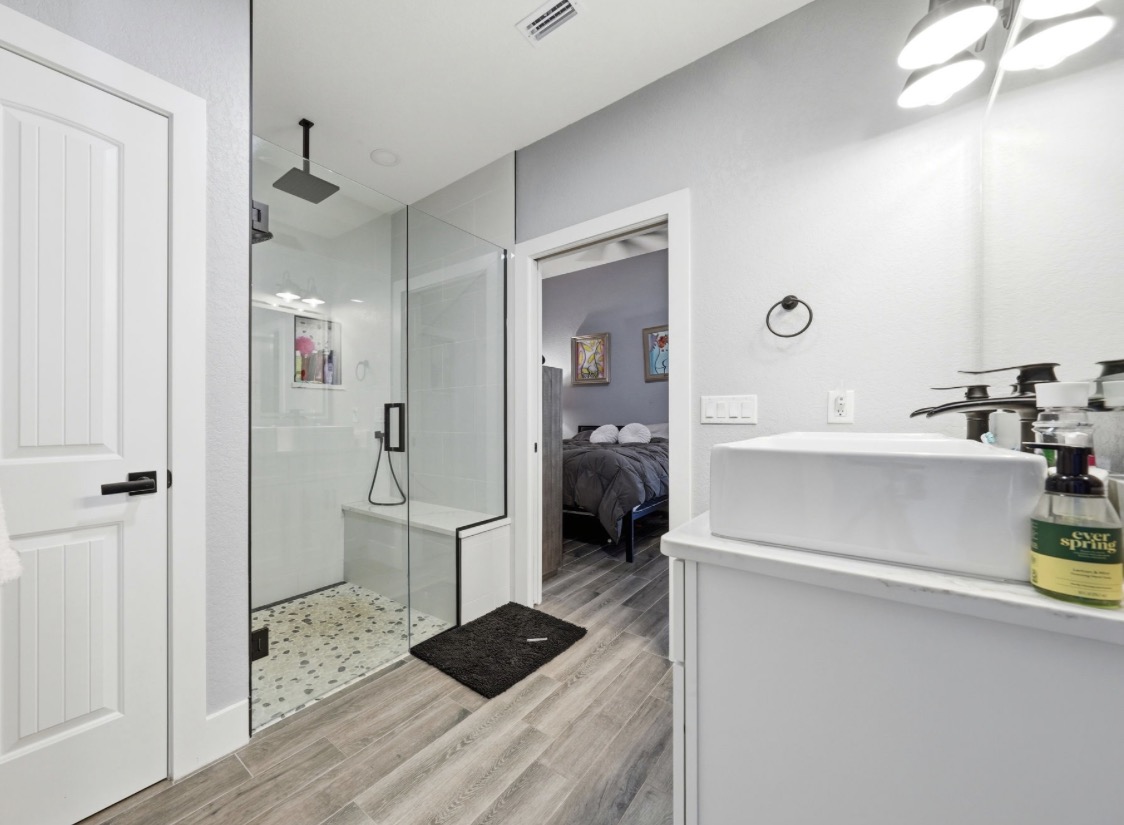 Bathroom with frameless glass walk-in shower, pebble tile floor, vessel sink and matte black fixtures