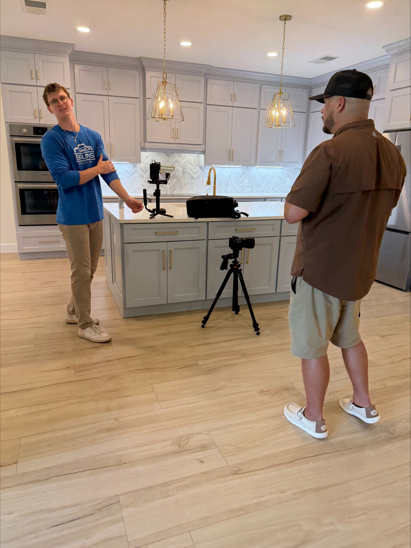 Two men filming a walkthrough video in a finished custom kitchen