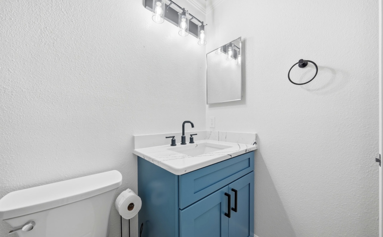 Powder bath with a blue shaker vanity, quartz top and matte black fixtures