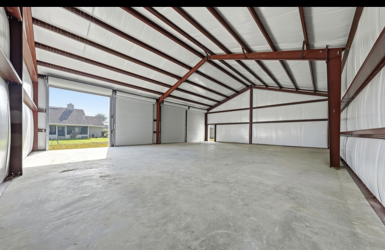 Interior of a red-iron steel building with clear-span framing, roll-up doors and a poured concrete slab