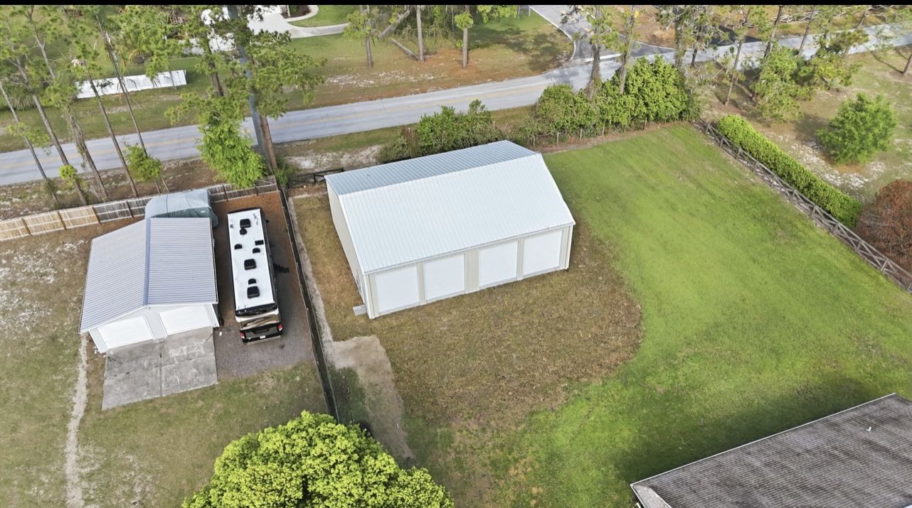 Aerial view of a four-bay metal garage beside a home with RV parking