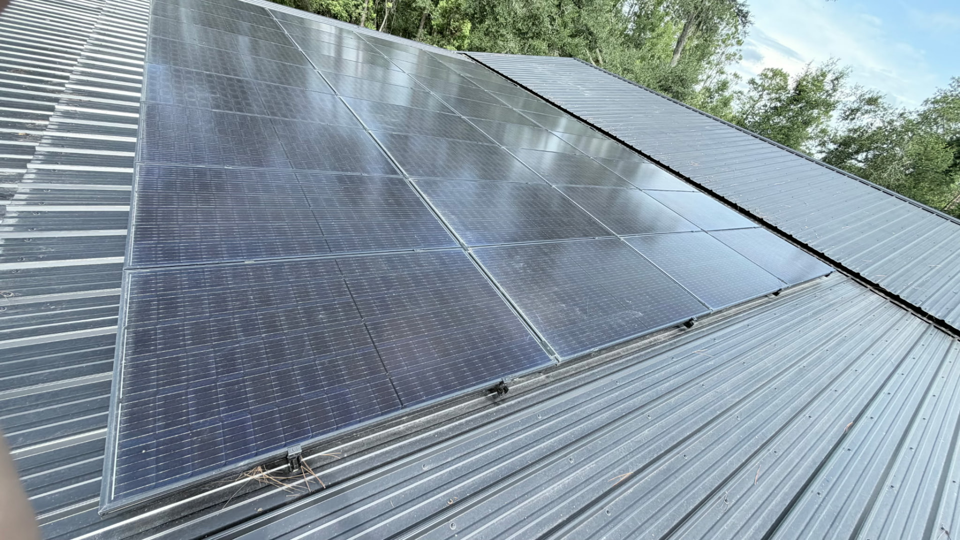 Angled view across a completed rooftop solar array on corrugated metal