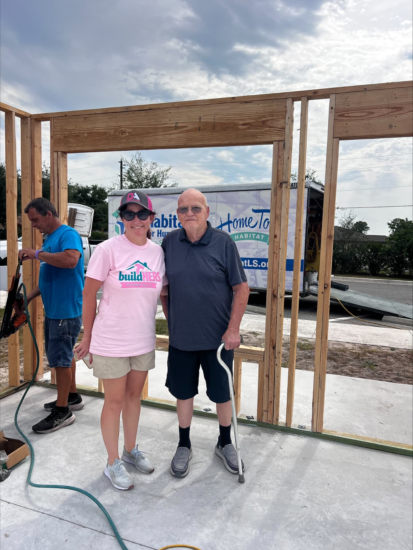 Volunteer standing with the future homeowner inside a newly framed Habitat for Humanity home