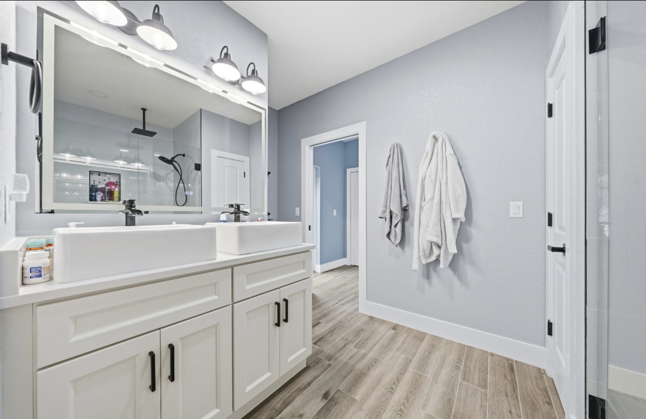 Bathroom with a double vessel-sink vanity, LED mirror and wood-look tile flooring