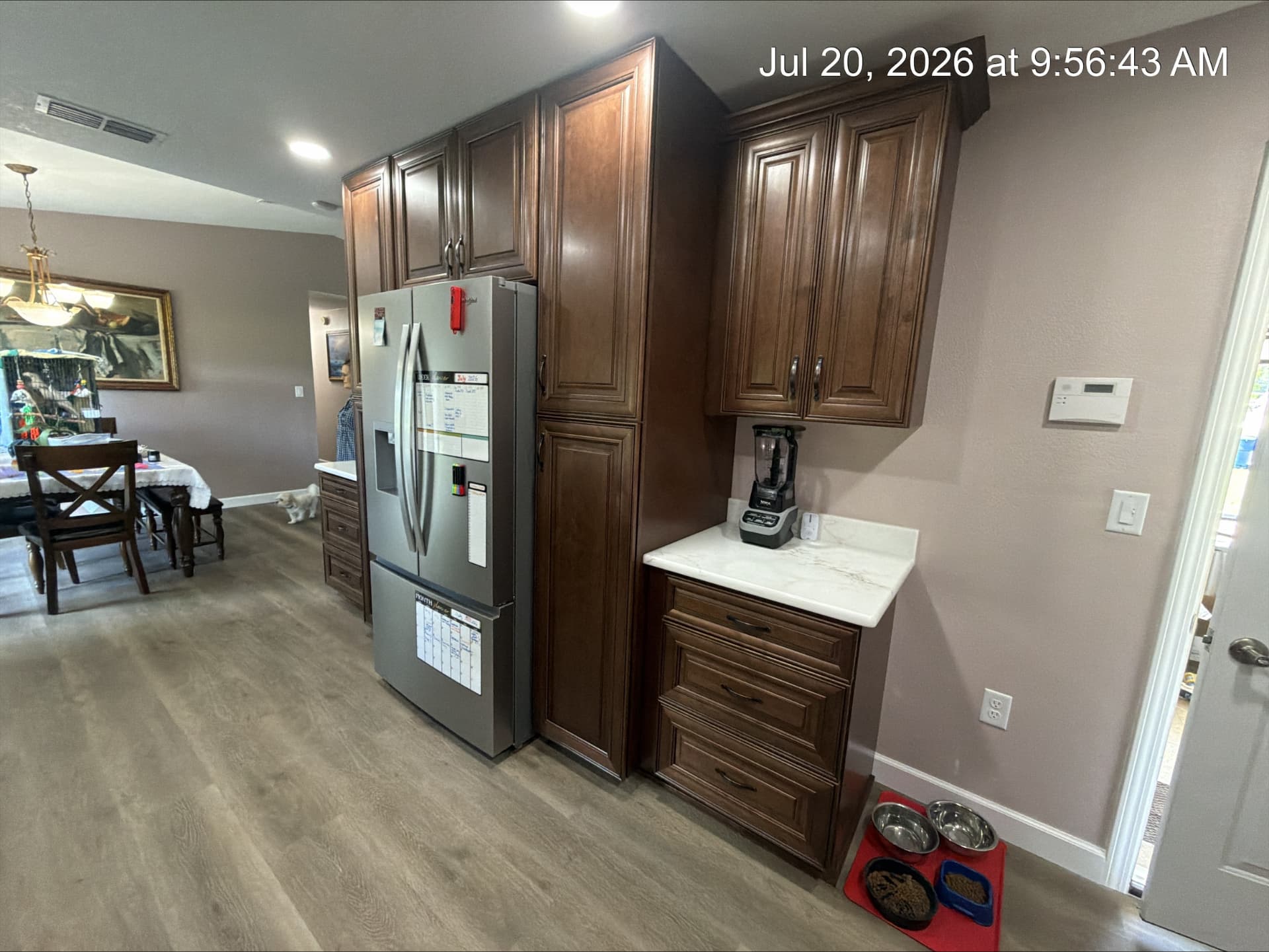 Walnut pantry tower beside a refrigerator with quartz-topped beverage station