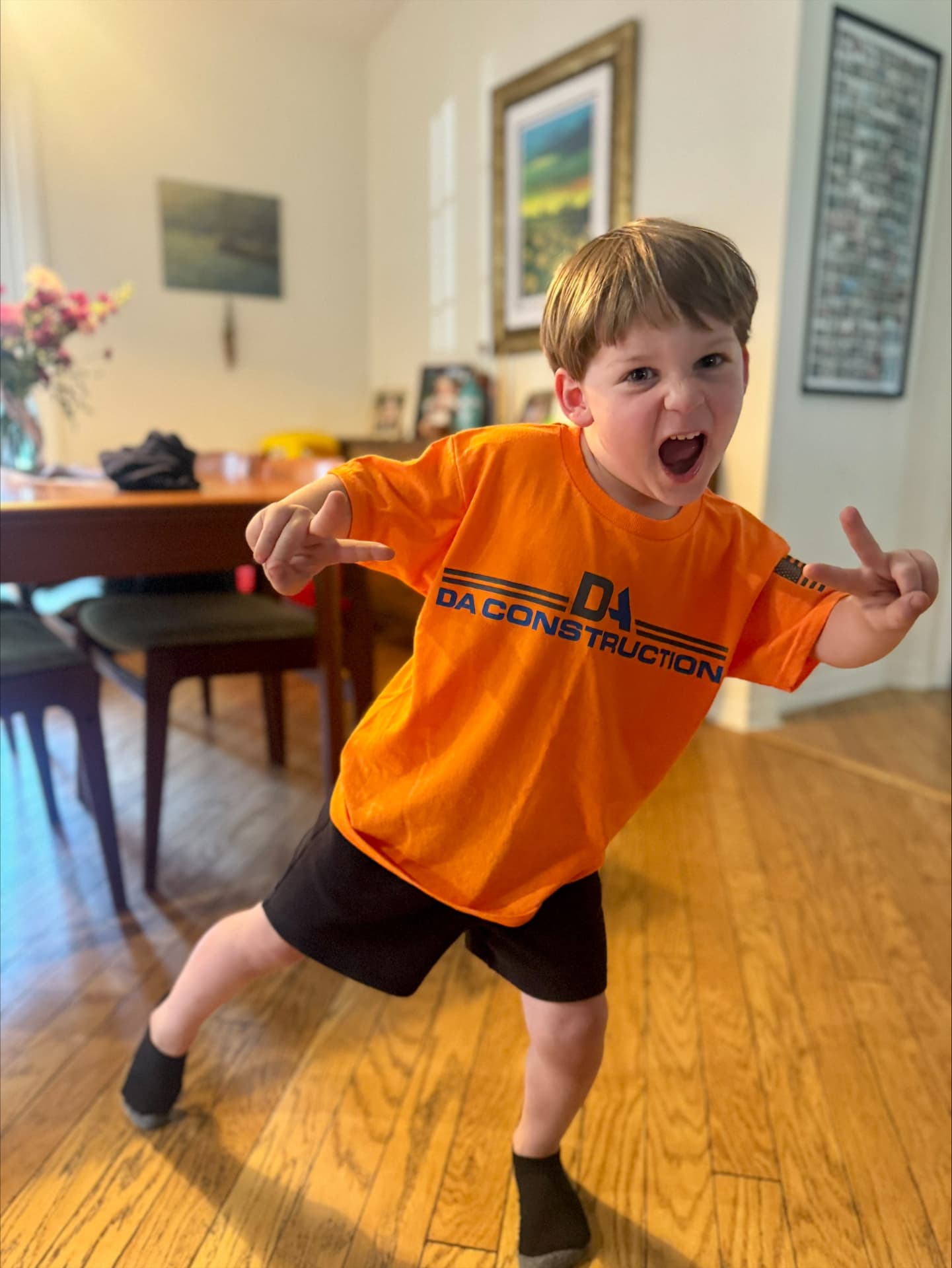 Child wearing an orange DA Construction t-shirt striking a playful pose
