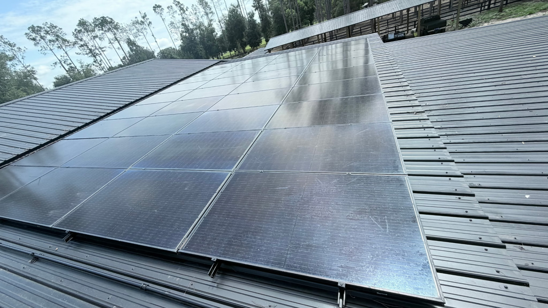 Solar array running up to the ridge of a metal roof with fenced pasture beyond