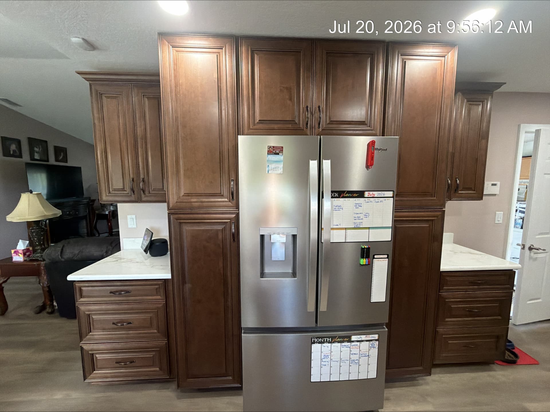 Built-in walnut refrigerator surround with flanking pantry towers and quartz counters
