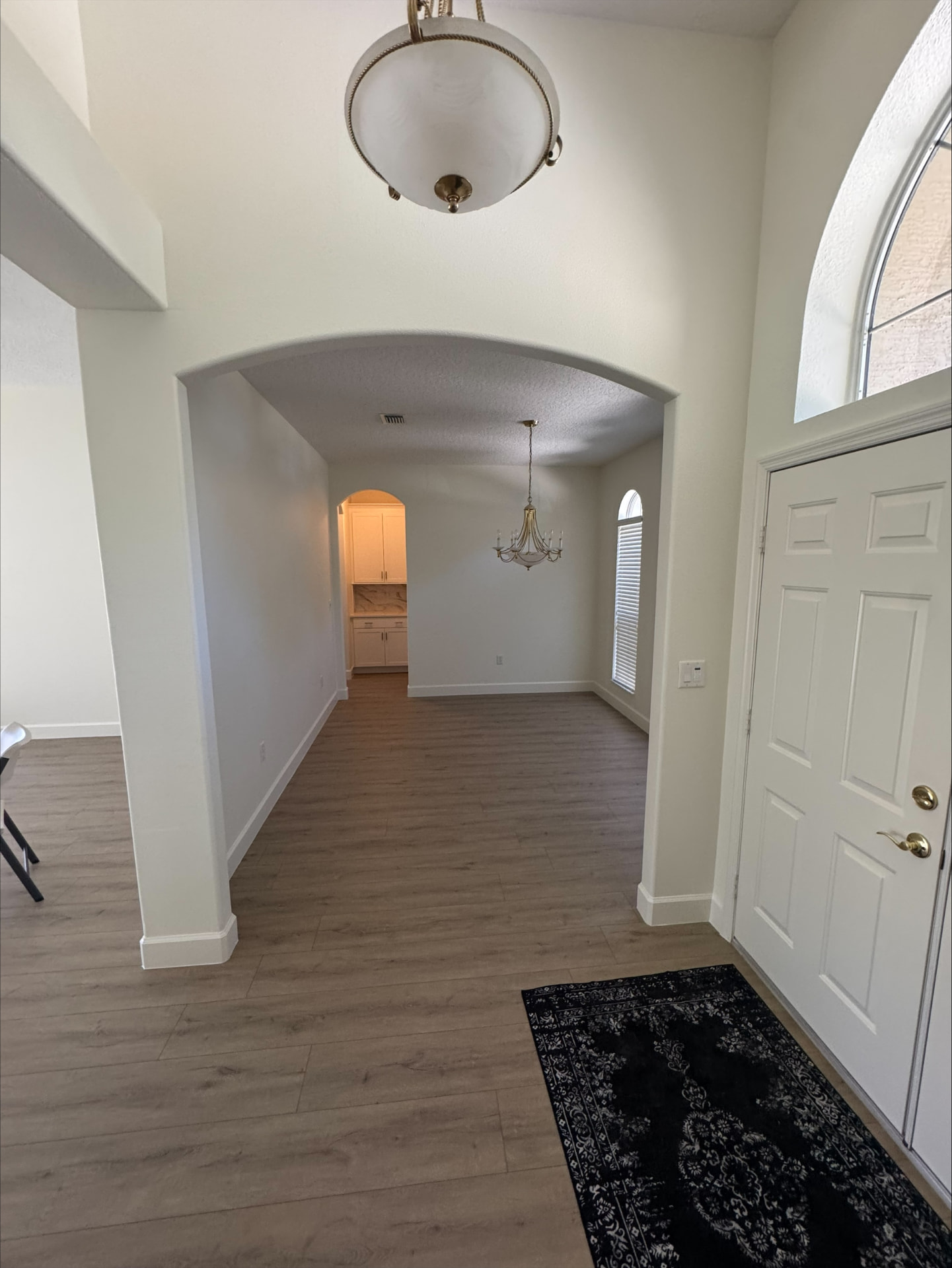 Freshly finished entry foyer with arched openings, chandelier and new wood-look plank flooring