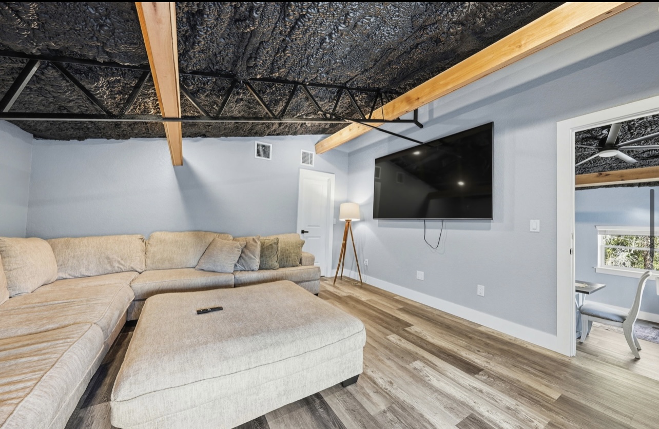 Media room with exposed truss ceiling, wood beams and a wall-mounted TV