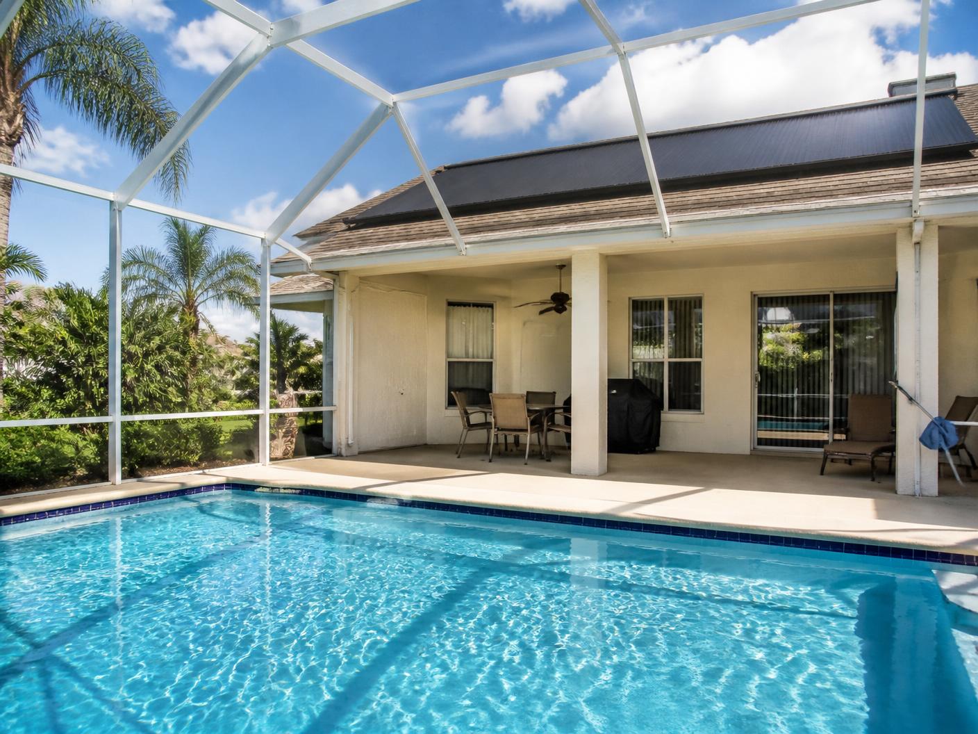 Screened Florida pool enclosure with solar pool heating panels mounted on the adjacent roof